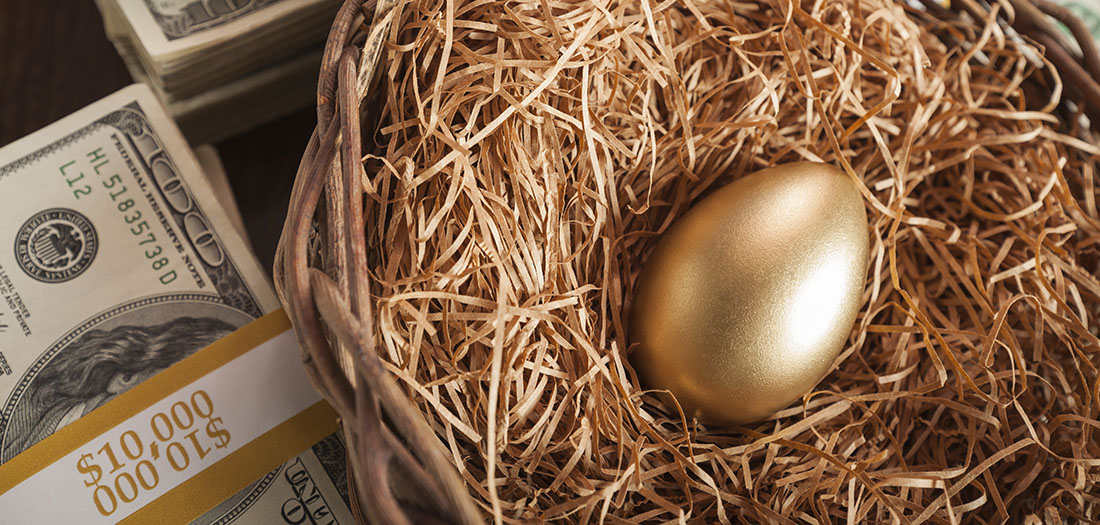 Golden egg in a nest next to a 10,000 dollar bundle of hundred dollar bills